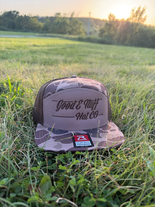 Deep Marsh camo flat bill hat with breathable mesh back and Good E Nuff branding in grassy outdoor setting