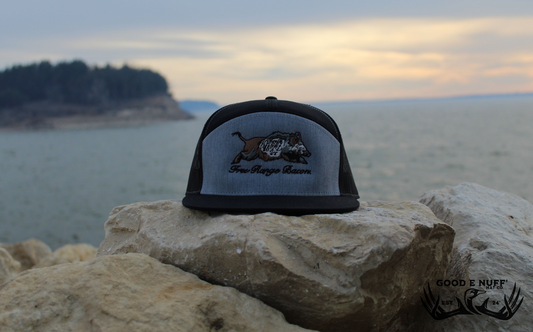 Free Range Bacon gray and black snapback hat with embroidered wild hog graphic on rocks by water