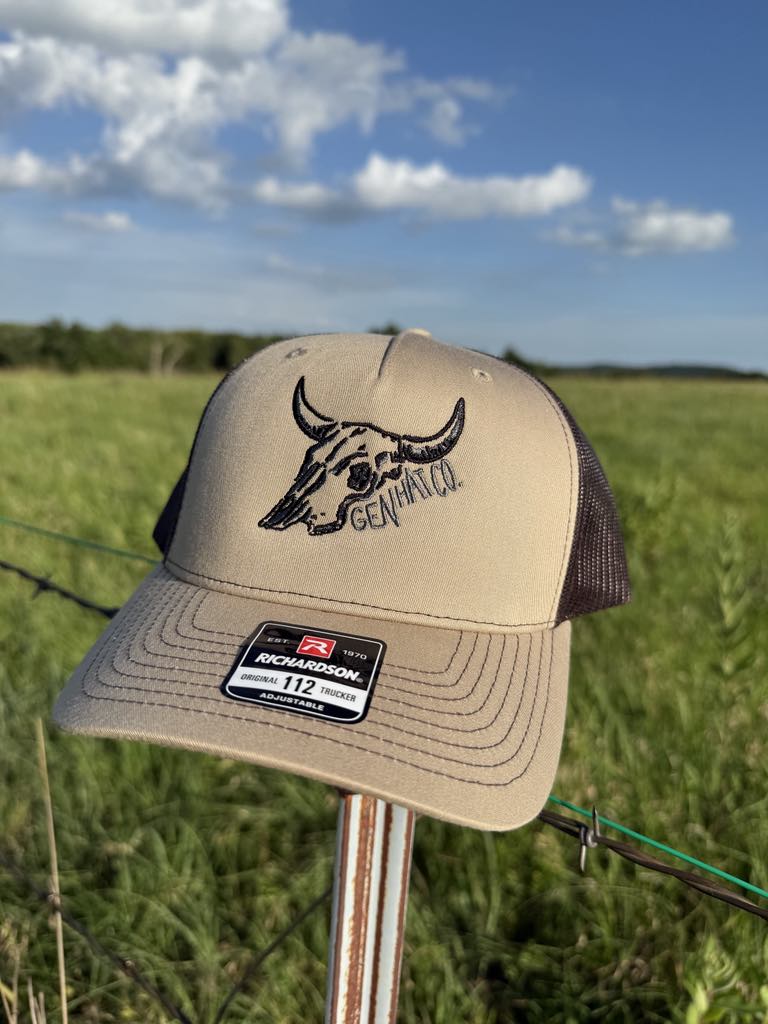 Tan and black Desert Proof hat with steer skull design and GEN HAT CO. mark on Richardson 112 trucker cap.