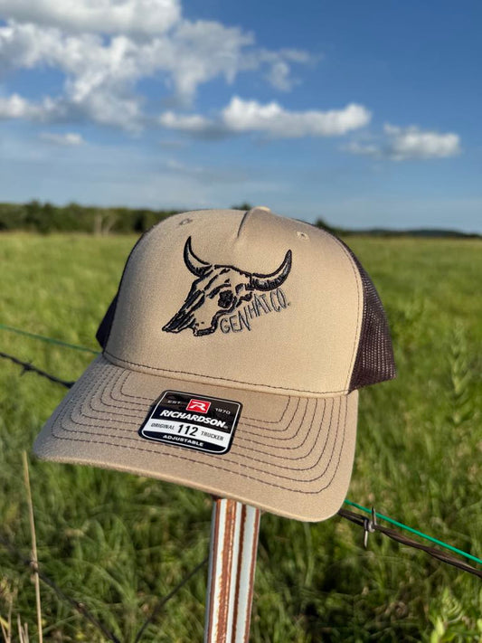 Tan and black Desert Proof hat with steer skull design and GEN HAT CO. mark on Richardson 112 trucker cap.