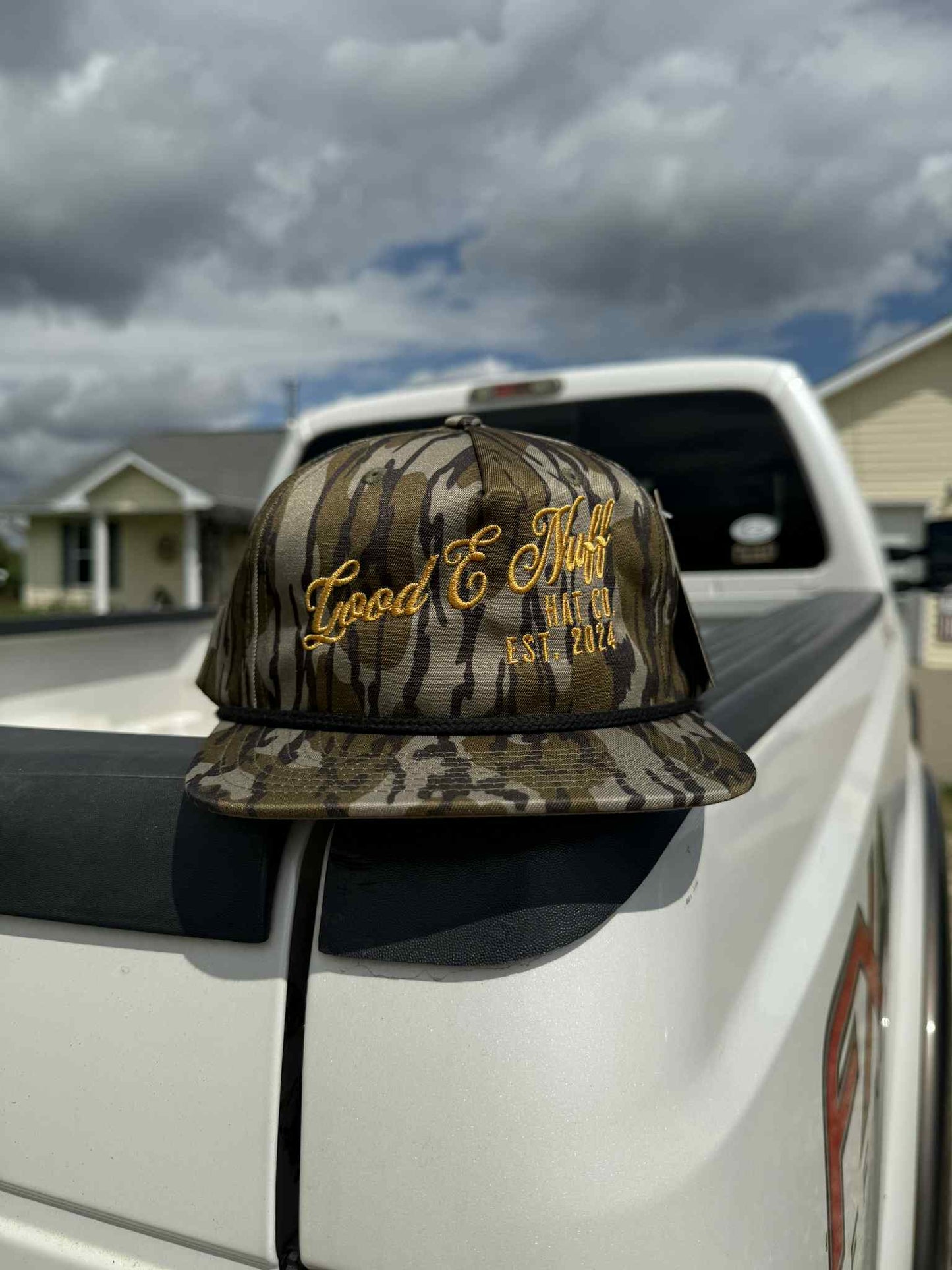 Vintage bottomland camo hat with golden "Good E Nuff Hat Co. Est. 2024" embroidery and structured crown on truck tailgate