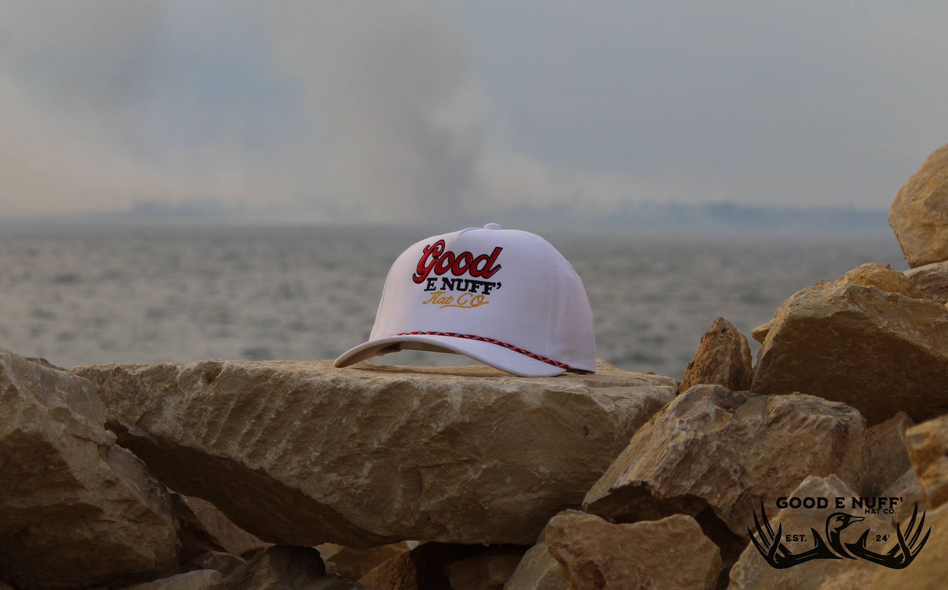 Up to No Good Elite premium hat on rocks by water, featuring Good E Nuff' Hat Co. design.
